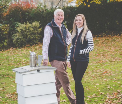 Emma Buckley and her father David smiling in front of a beehive at Buckley’s Bees Cheshire apiary